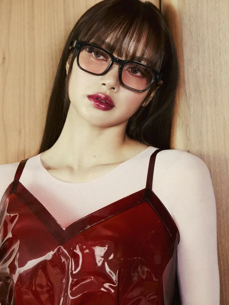 ลิซ่าใส่แว่น Meta Adventurer LISA Edition เลนส์ชมพู กับชุดไวนิลสีแดง พิงผนังไม้