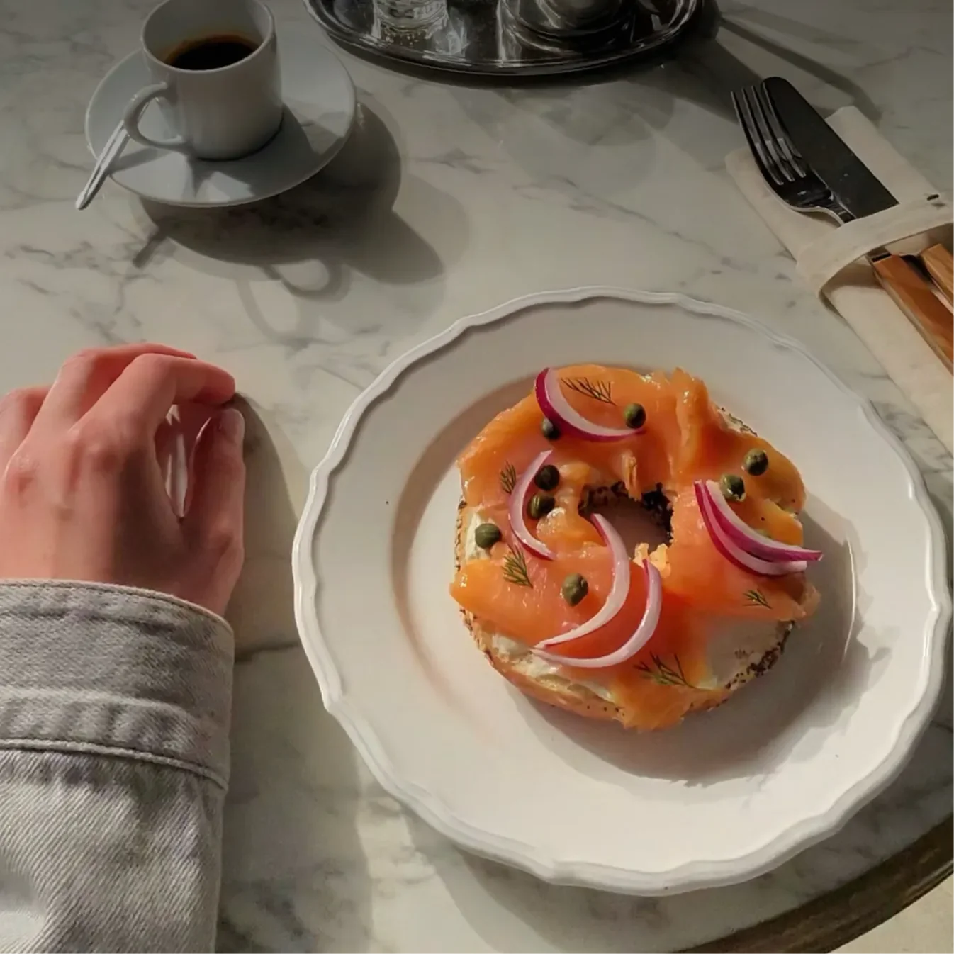 ภาพมุมมองผู้สวมแว่นมองลงบนโต๊ะ มีกาแฟและเบเกิล ภาพตัวอย่างจาก Meta
