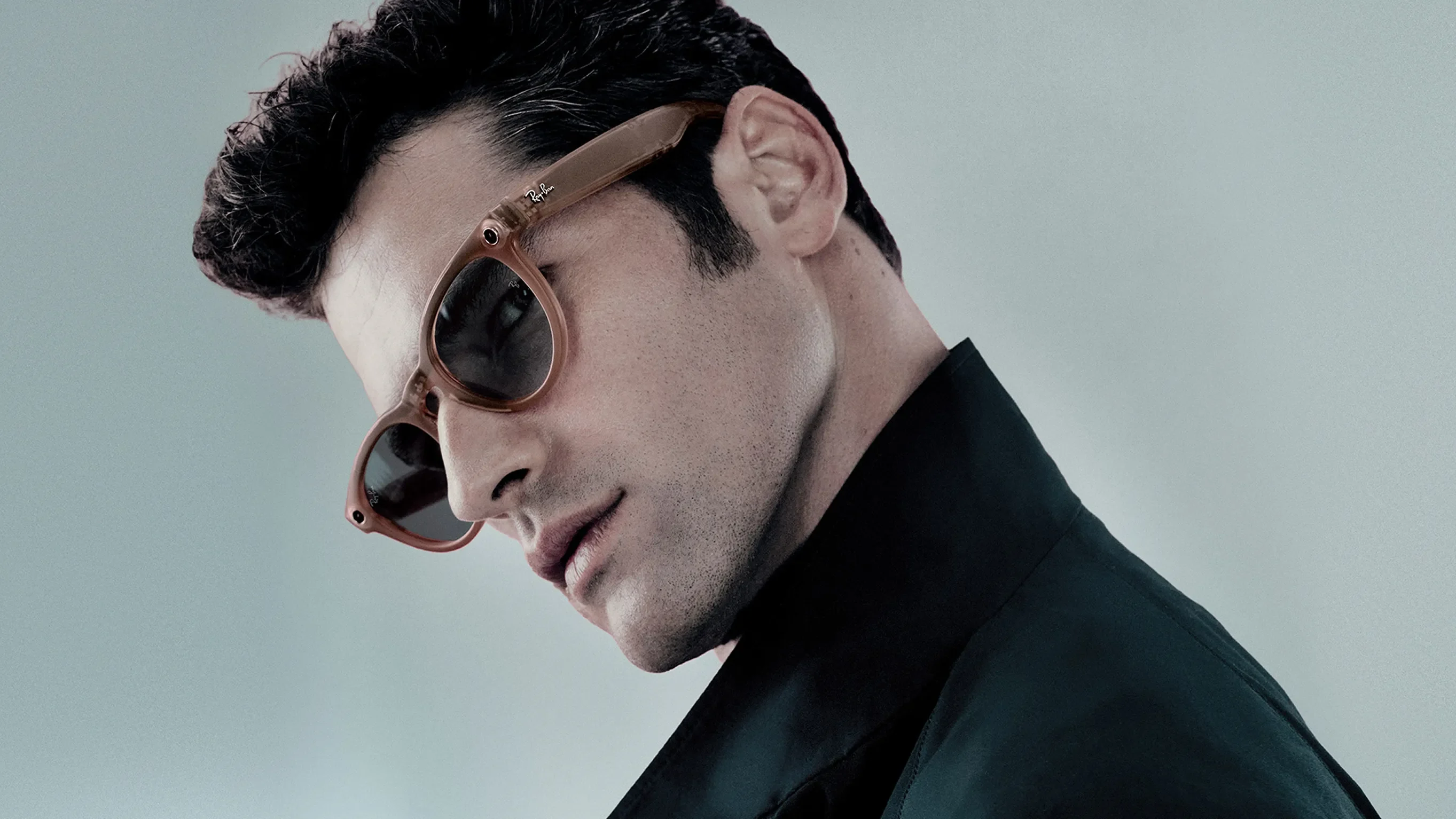 Model wearing Rayban Meta Headliner glasses with Matt Peach frames with Grey Transitions® lenses.